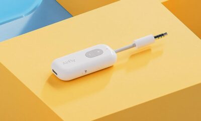 A white wireless twelve south headphone adapter with a plus and minus button lies on a dual-shade yellow background, with text "AirFly" printed on its side.